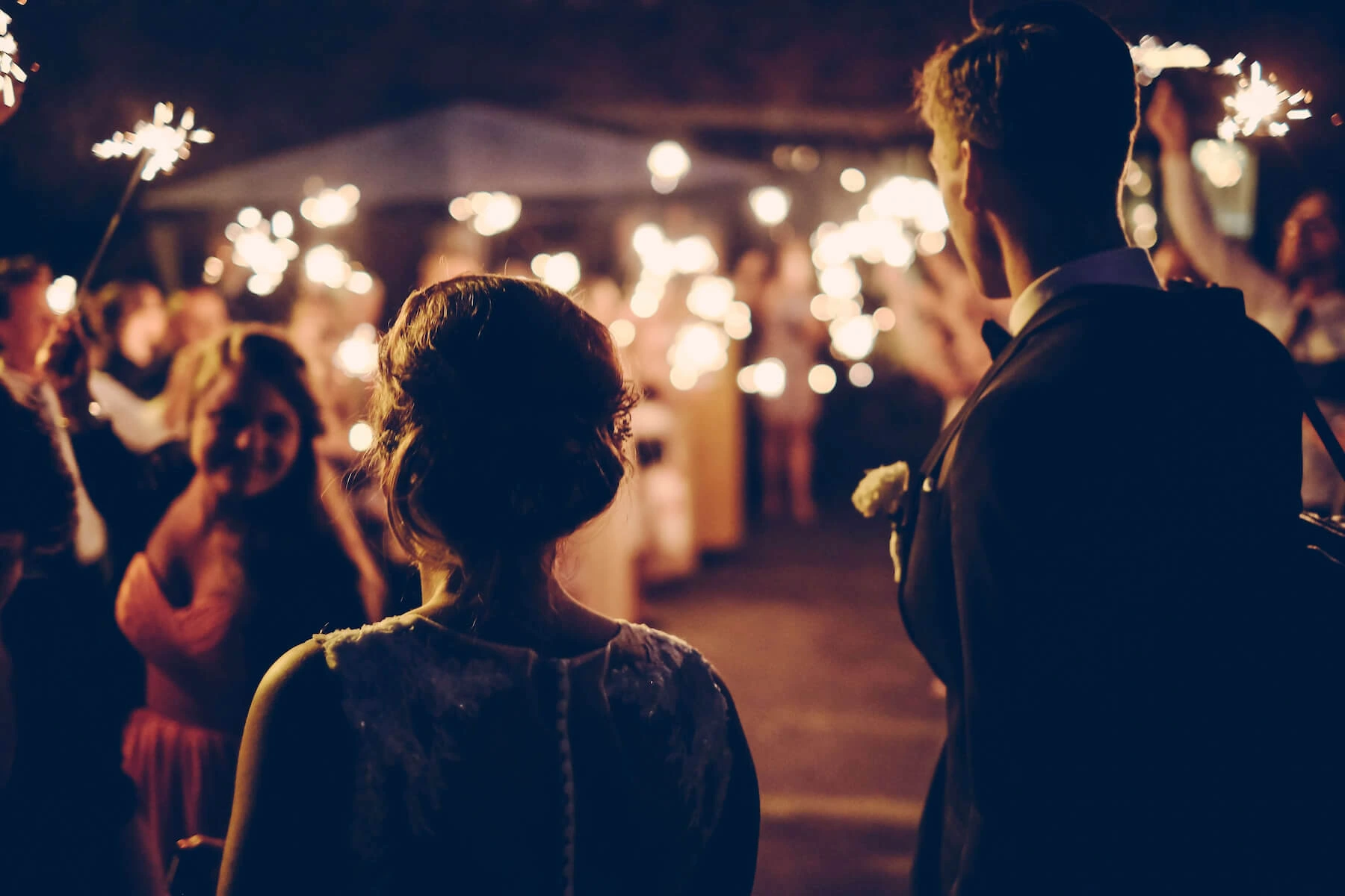 Bridge and groom walking down a row of guests - all holding sparklers